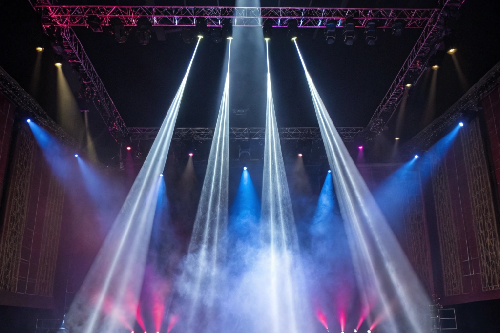 A stage filled with sharp, colorful beams of light from BEAM moving heads cutting through haze.