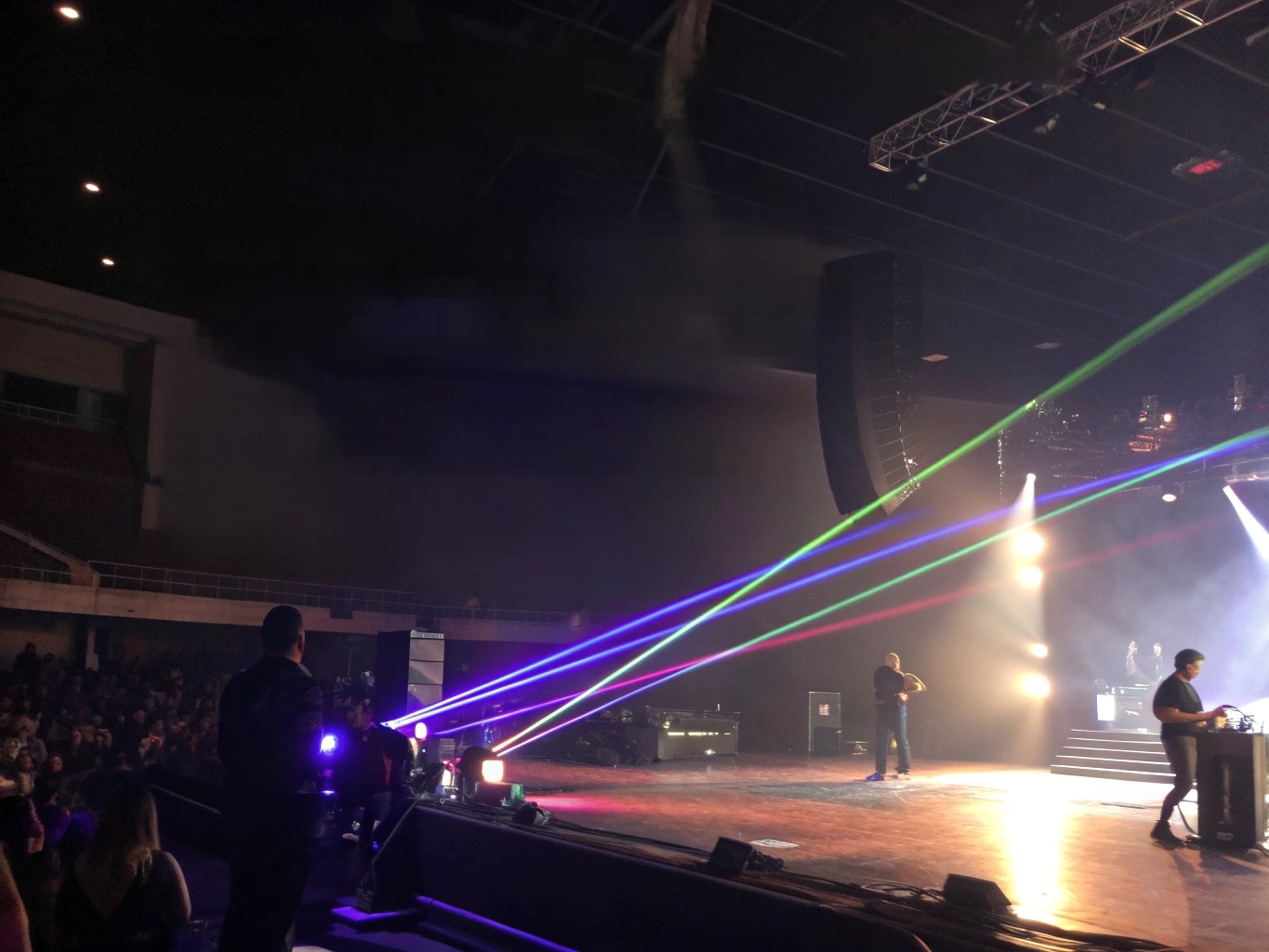 Essential Knowledge for Stage Laser Lighting A professional laser light projector in a dark room, emitting sharp, multi-colored beams through haze.